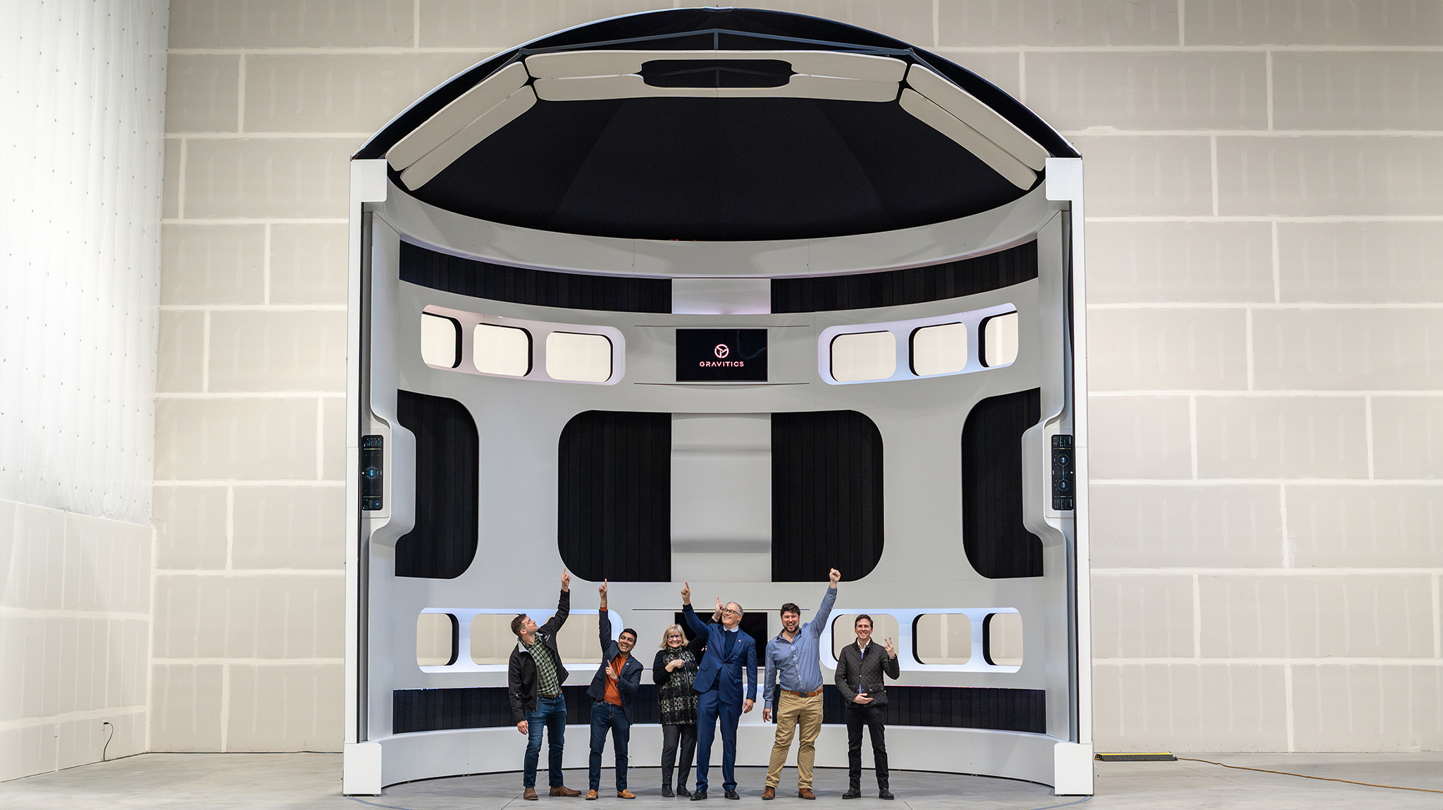 Gov. Inslee and Gravitic staff stands in a large model of a space station in Gravitics' facility. 
