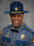 Chief Batiste, a Black man, in full uniform, including hat. 