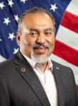David Puente, a man, wearing a suit with the American Flag in the background