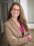 Photo of Tana Senn, a woman wearing glasses and a pink shirt under a tan blazer.