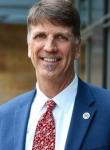 Smiling Tim Lang, a man, wearing a blue suit with red patterned tie