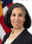 Angela Ramirez in front of an American flag wearing a black blazer and white top