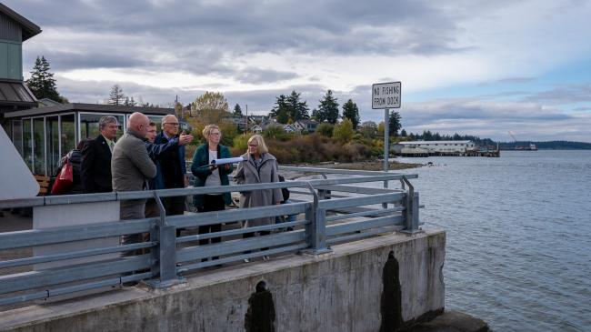 Gov. Jay Inslee and First Spouse Trudi Inslee stand by a ferry dock on Puget Sound.